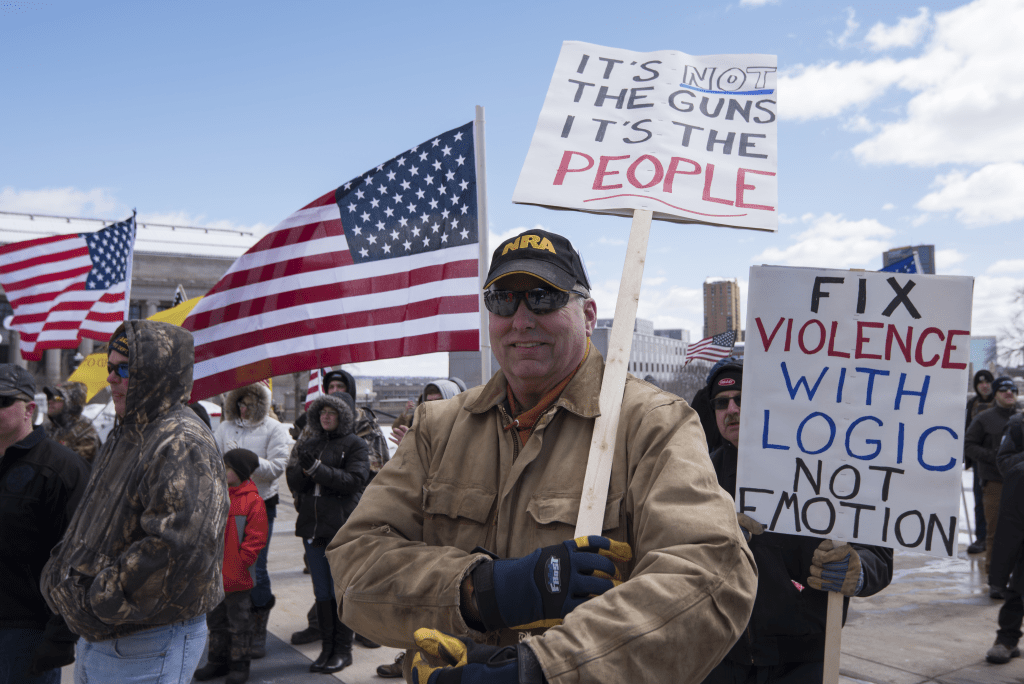 People attending a Second Amendment rally holding pro-gun rights signs and American flags